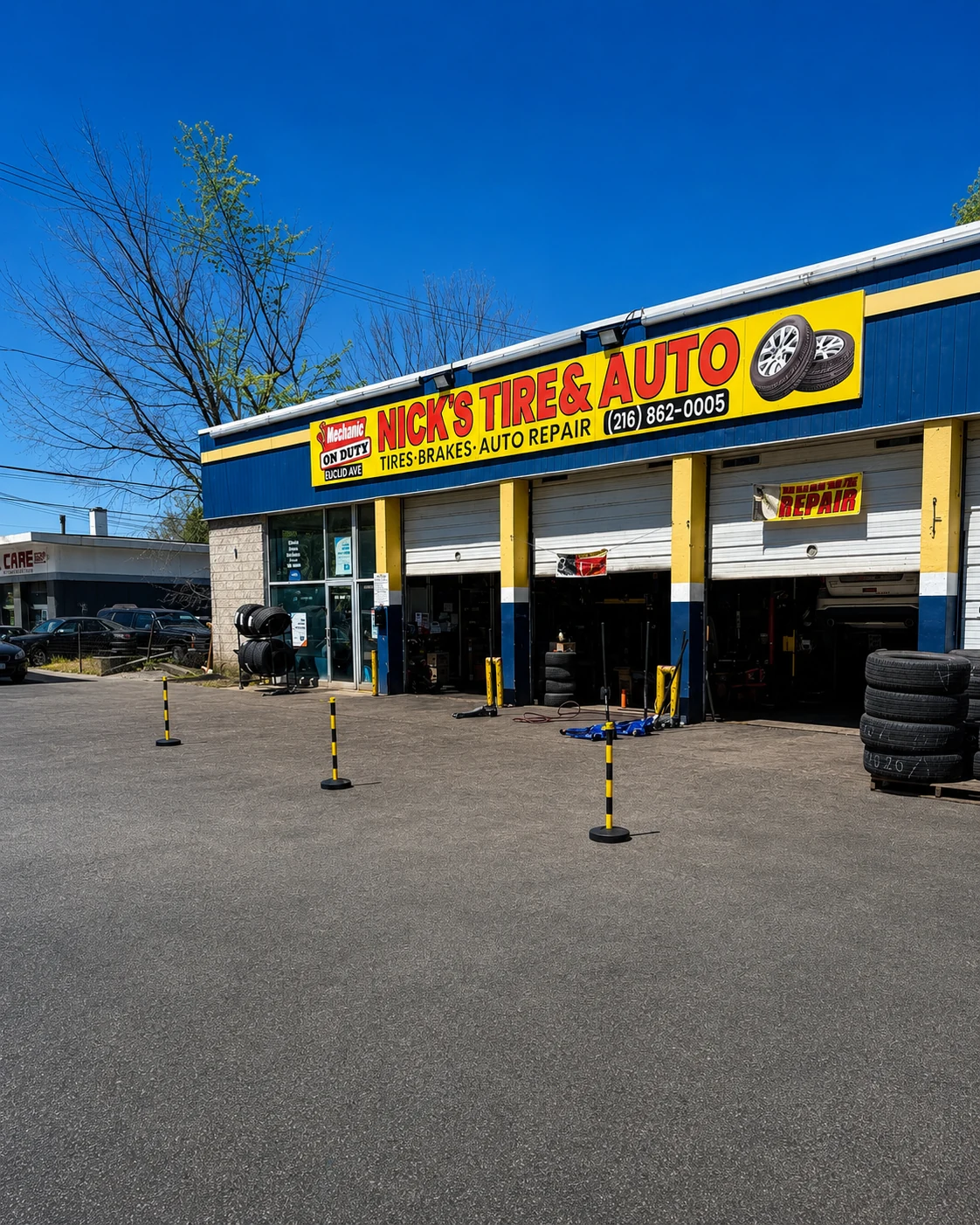 Nick's Tire & Auto exterior with yellow and black lane cones, open bays, and tire stacks